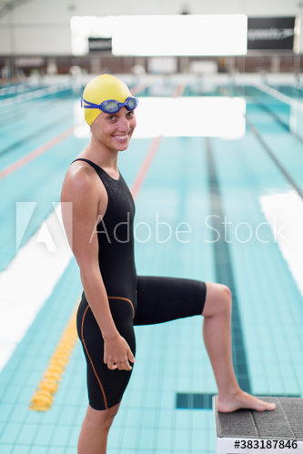Portrait confident female swimmer at swimming pool starting block