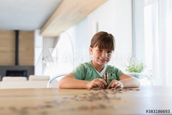 Portrait confident girl counting and stacking coins at dining table