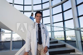 Portrait confident male doctor on modern hospital steps
