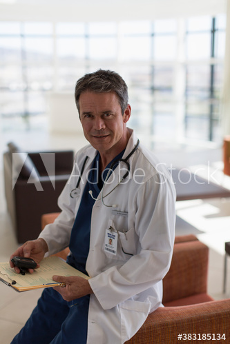 Portrait confident male doctor with pager in hospital lobby