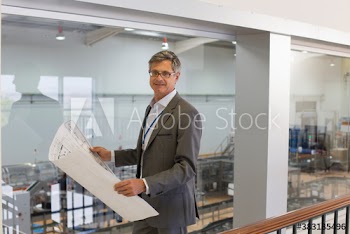 Portrait confident male engineer with blueprints above factory floor