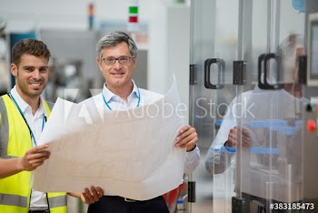 Portrait confident male engineers with blueprints in factory