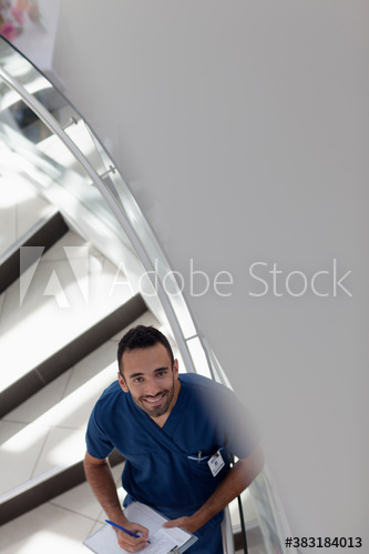 Portrait confident male nurse with clipboard on hospital staircase