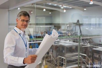 Portrait confident male supervisor with blueprints above factory floor