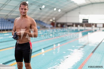 Portrait confident male swimmer at indoor swimming pool