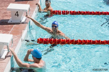 Portrait confident male swimmer preparing for competition in sunny pool