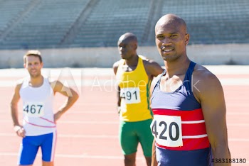 Portrait confident male track and field athletes sunny running track