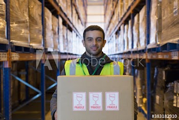 Portrait confident male worker carrying box in distribution warehouse