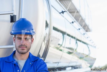 Portrait confident male worker in front of milk tanker