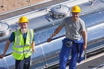 Portrait confident male workers above milk tanker