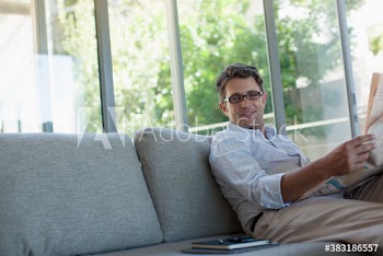 Portrait confident man reading newspaper on sofa