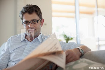 Portrait confident man reading newspaper on sofa