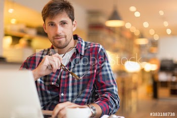 Portrait confident man working at laptop in cafe