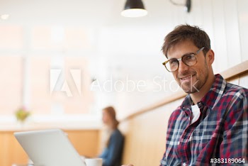 Portrait confident man working at laptop in cafe