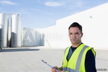Portrait confident manager with clipboard near storage tanks