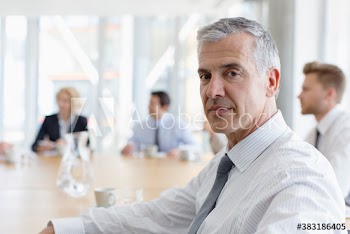 Portrait confident mature corporate businessman in meeting