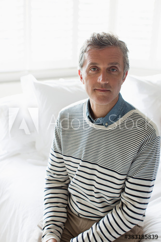 Portrait confident mature man sitting on bed