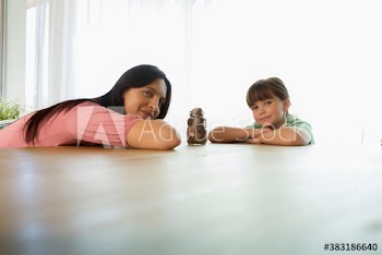 Portrait confident mother and daughter with jar of coins