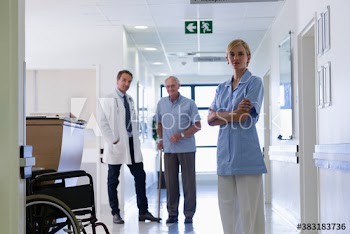 Portrait confident nurse with doctor and senior patient in hospital corridor