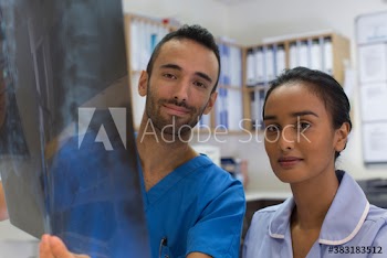Portrait confident radiologist and nurse looking at x-ray in clinic