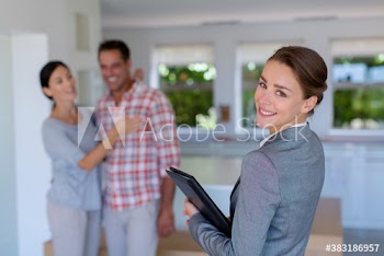 Portrait confident realtor with couple in new house
