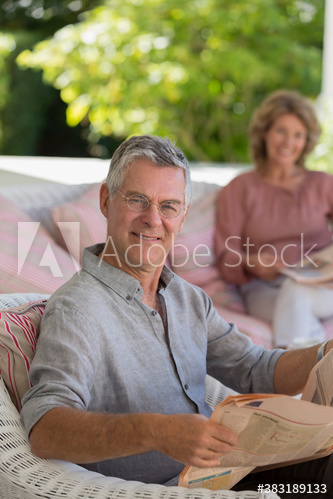 Portrait confident senior man reading newspaper on patio