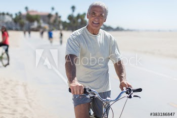 Portrait confident senior man riding bicycle on sunny beach boardwalk