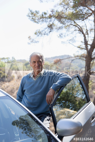 Portrait confident senior man standing outside car at roadside