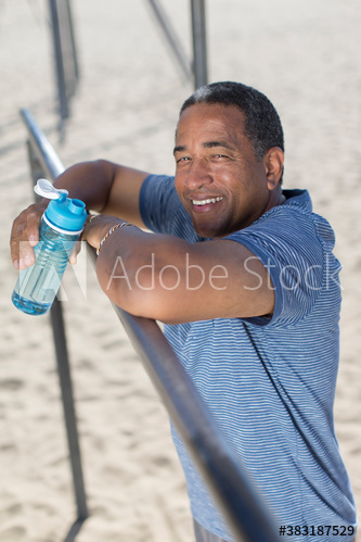 Portrait confident senior man with water bottle exercising on beach