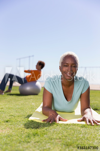 Portrait confident senior woman practicing yoga in sunny grass