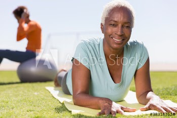 Portrait confident senior woman practicing yoga on sunny lawn