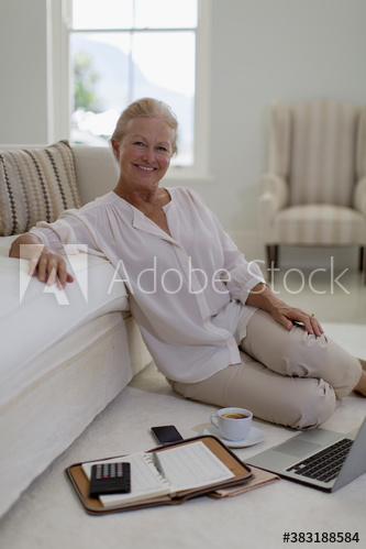 Portrait confident senior woman using laptop on living room floor