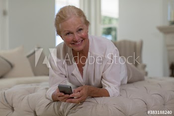 Portrait confident senior woman using smart phone on ottoman