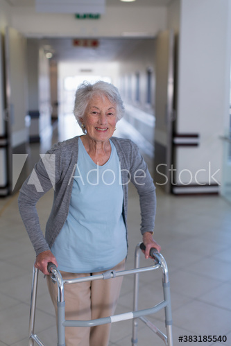 Portrait confident senior woman with walker in hospital corridor