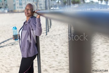 Portrait confident senior woman with water bottle exercising on beach