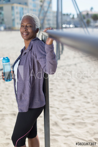 Portrait confident senior woman with water bottle exercising on beach