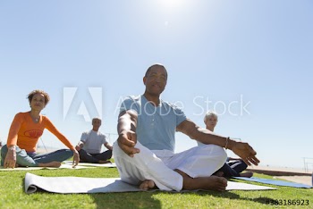 Portrait confident seniors practicing yoga meditation on sunny lawn