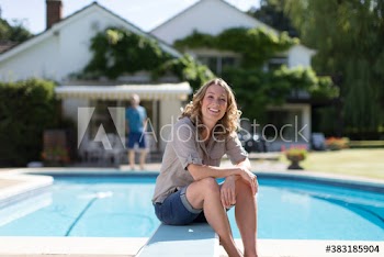Portrait confident woman relaxing at sunny poolside