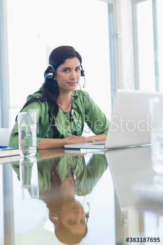 Portrait confident woman with headphones working at laptop