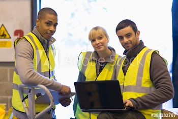 Portrait confident workers with laptop meeting in warehouse