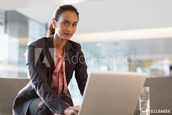 Portrait confident young corporate businesswoman at laptop in office