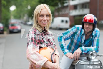 Portrait confident young couple with helmets and motor scooter