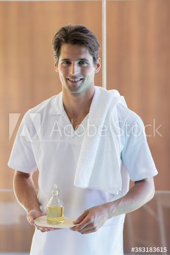 Portrait confident young male masseuse holding massage oil