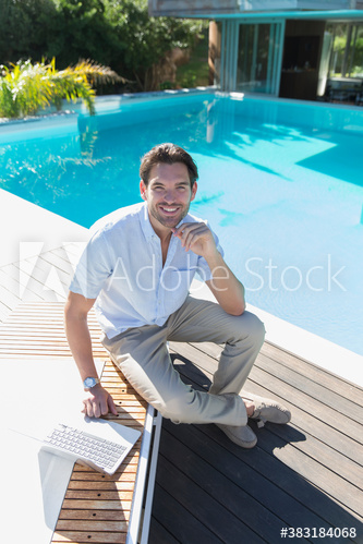 Portrait confident young man using laptop at sunny poolside