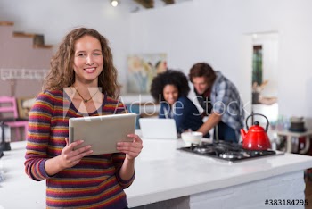Portrait confident young woman using digital tablet in apartment kitchen