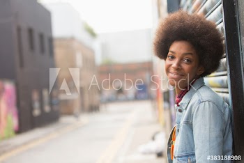 Portrait confident young woman with afro on city street