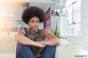 Portrait confident young woman with afro on sofa