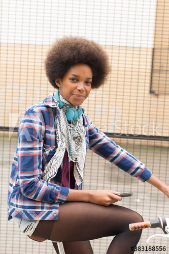 Portrait confident young woman with afro riding bicycle