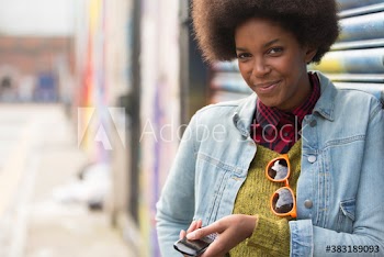 Portrait confident young woman with mobile phone on city street
