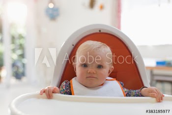 Portrait cute baby girl in high chair